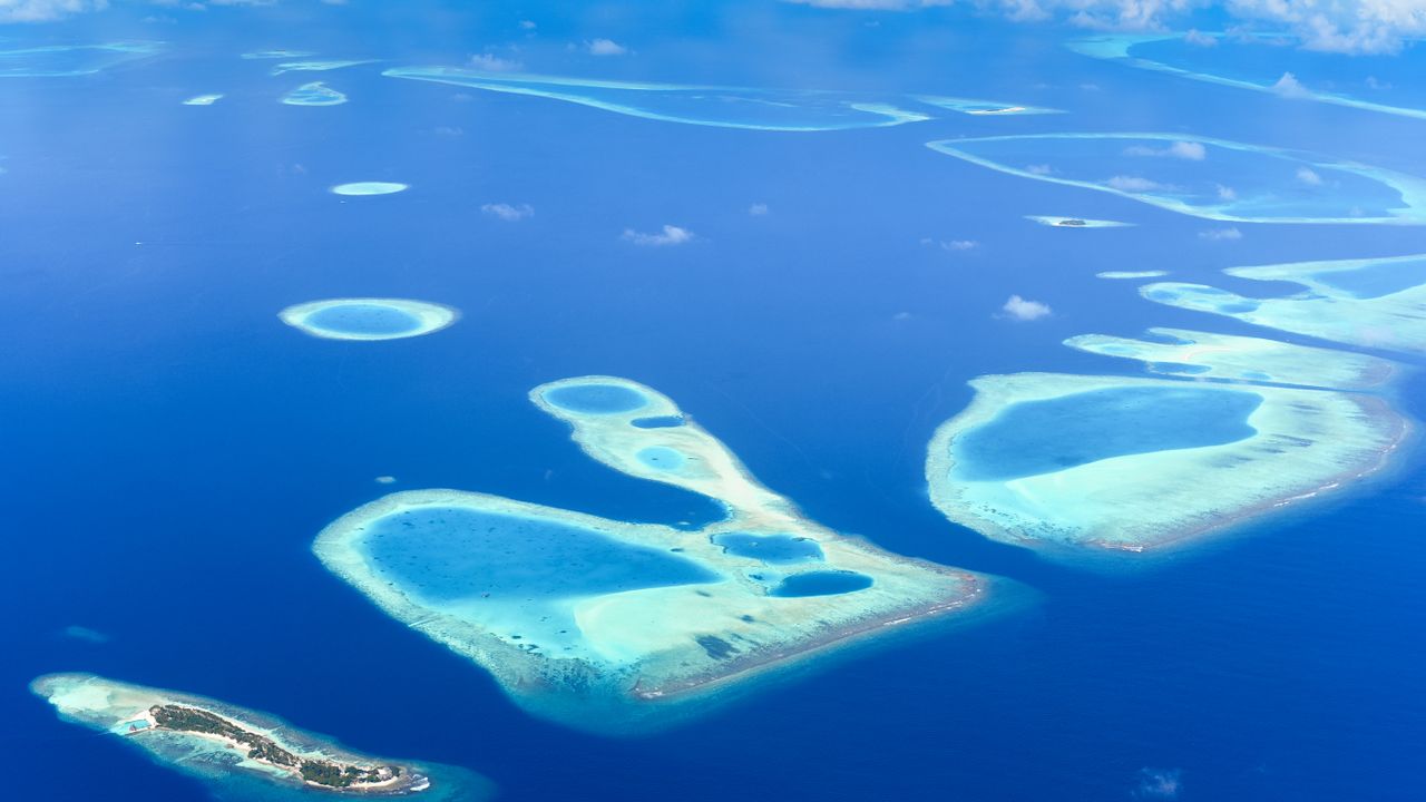A breathtaking aerial view of the Maldives' turquoise atolls surrounded by deep blue ocean.